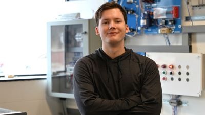 Student in an electrical technology lab standing in front of electrical equipment mounted to a wall