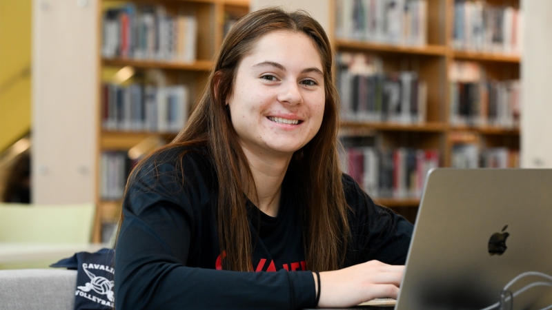 A student studying on her laptop in the library.