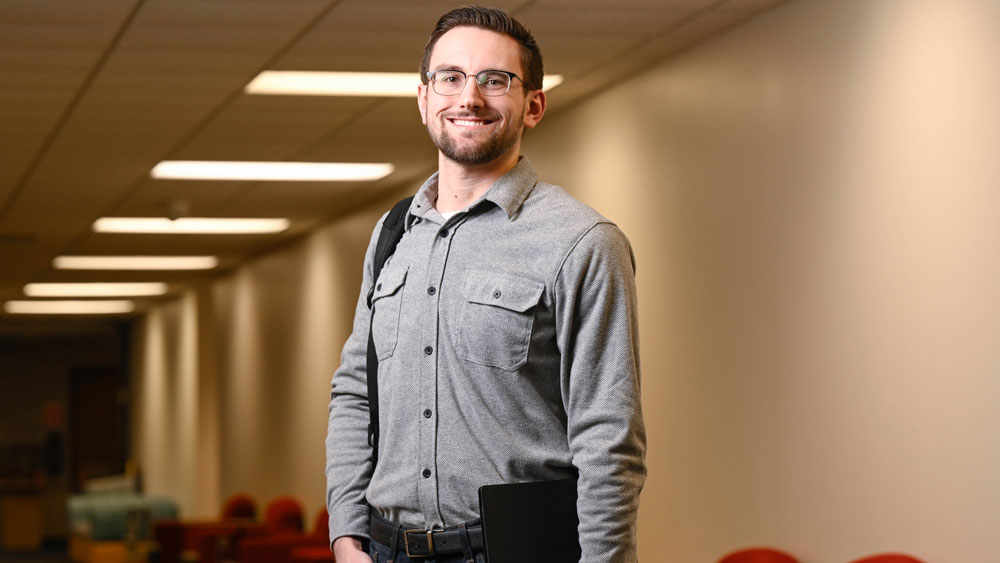 Student holding a binder smiling in a hallway at KCC