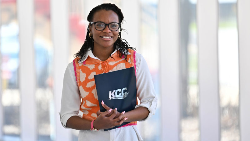 Indoor candid of a student holding a binder in glass hallway